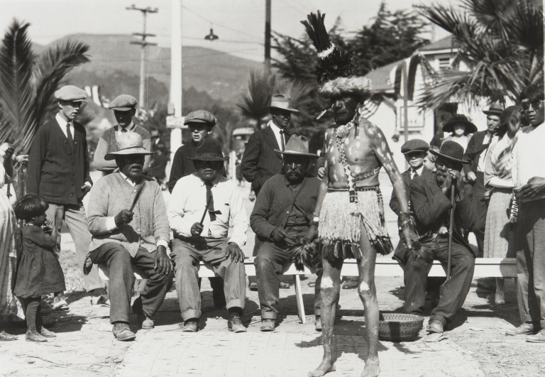 Dance performance by Bob Bautista (Tachi Yokuts) at Ventura County Fair : 1932, accompanied by men with clapper sticks. Left to right on bench: Jim Wilcox (Yokuts), unidentified man, Jose Juan Olivas (Ventureño Chumash), and Juan Solano (Migueleño Salinan).