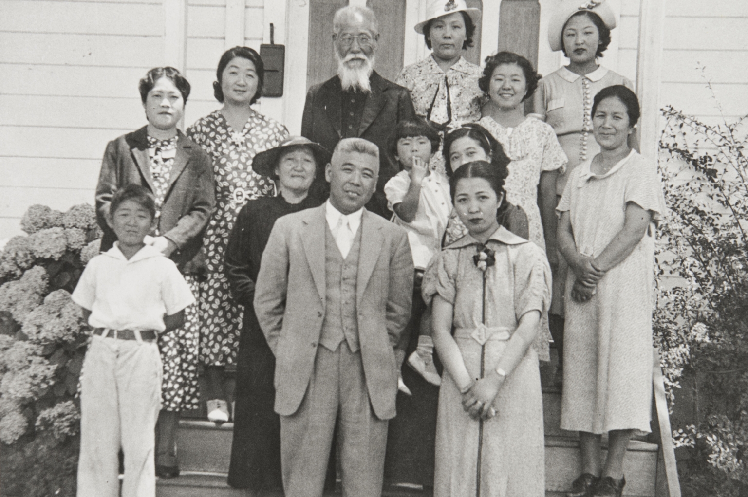 Japanese Methodist Church, A Street, Oxnard : 1937. Clockwise from far left around outside: Calvin Machida, Mrs. Yasuye Takasugi, Mrs. Machida, Rev. K Babu (founder and first minister of church), Mrs. Yamada, Faye Hirata, Tsuruka Yamada, Mrs. Kawata, Mrs. Mano & Mr. Mano. In middle on left: Mrs. Otani (wearing hat), woman holding child not identified.